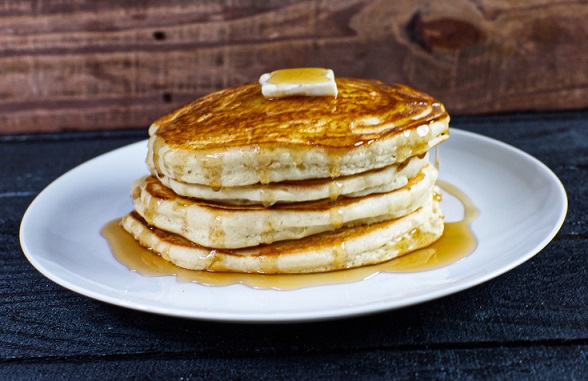 A stack of fluffy pancakes with butter and syrup.