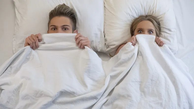 Lovers caught in bed by parents, embarrassed and frightened, looking shocked